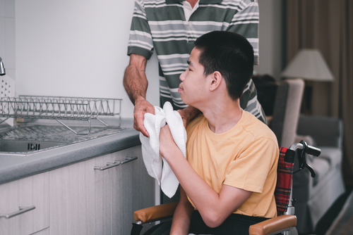 Young person sitting in a wheelchair helping with kitchen cleanup