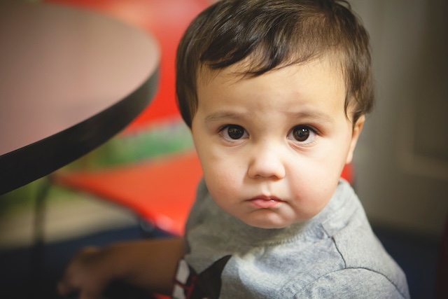 A small child with beautiful wide eyes staring directly into the camera.