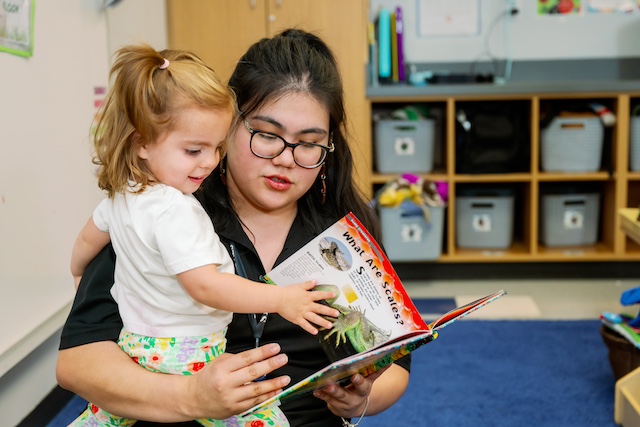 A young child being held by a therapist interacting with a book